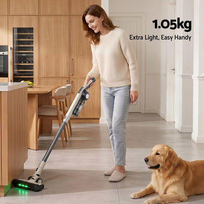 Woman using a vacuum cleaner in a kitchen with a dog sitting nearby, emphasizing the vacuum's light weight.