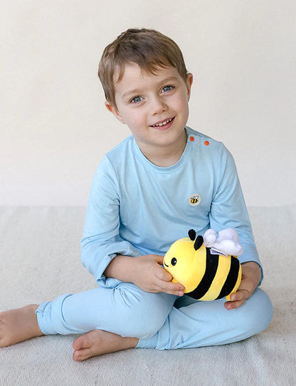 Boy in a light blue organic bamboo pyjama set holding up a gold silk mitten — eczema-friendly