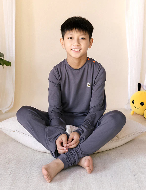 Child wearing a charcoal eczema-friendly organic bamboo long-sleeve pyjama set with bee logo