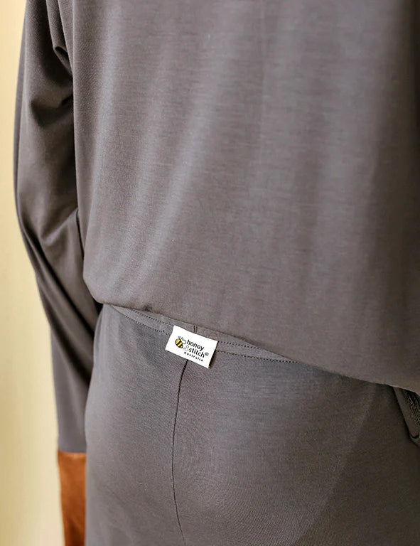 Detail of the tag-free Honey & Stitch label on a dark gray organic bamboo pyjama set
