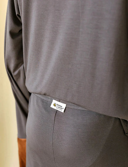 Detail of the tag-free Honey & Stitch label on a dark gray organic bamboo pyjama set
