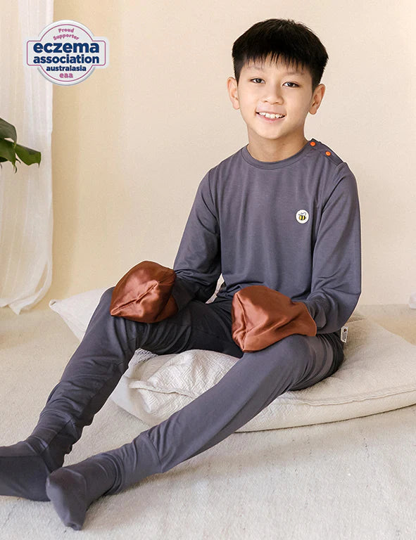 Boy in a dark gray organic bamboo pyjama set with fold-over silk mittens — eczema-friendly