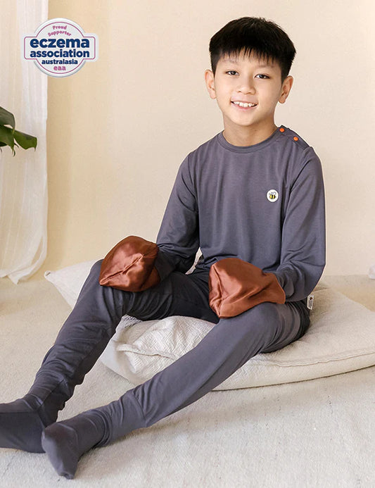 Boy in a dark gray organic bamboo pyjama set with fold-over silk mittens — eczema-friendly