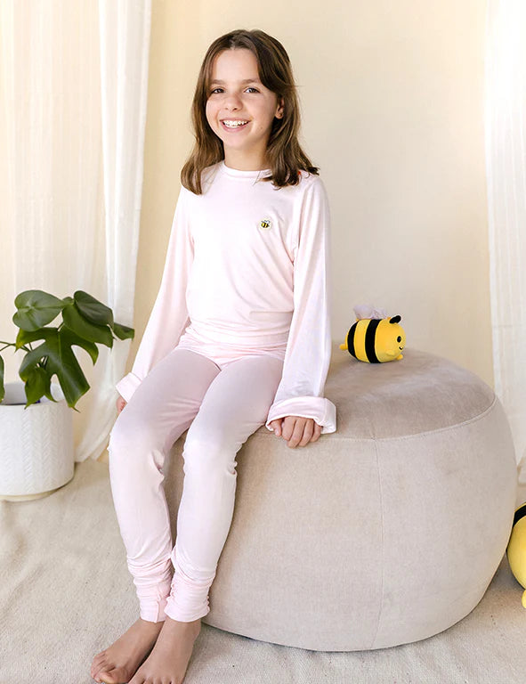 Girl in a pink eczema-friendly organic bamboo long-sleeve pyjama set with bee logo, by Honey & Stitch
