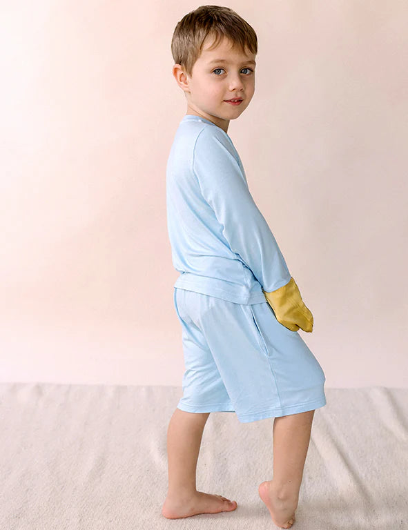 Side view of a boy in blue organic bamboo kids' shorts showing the side pocket — eczema-friendly by Honey & Stitch